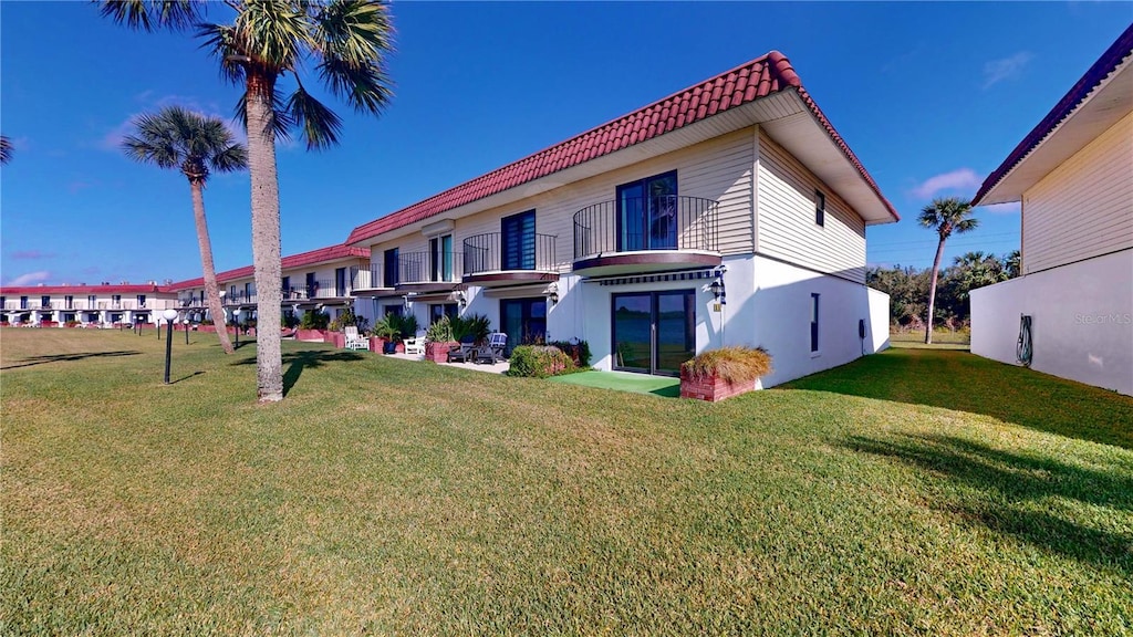 back of property featuring a balcony and a yard