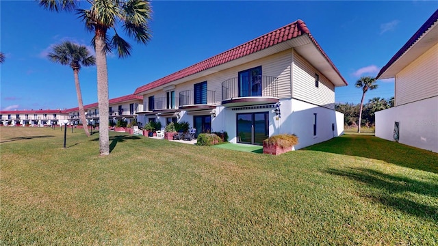 back of property featuring a balcony and a yard