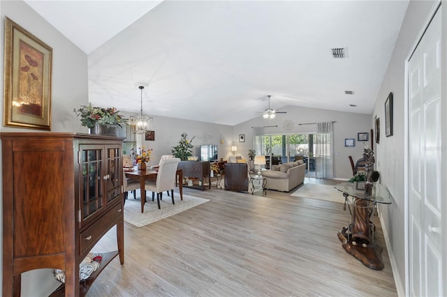 living room with ceiling fan with notable chandelier, vaulted ceiling, and light wood-type flooring