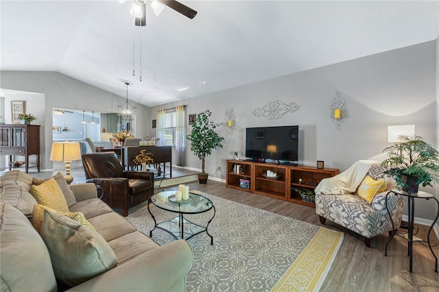 living room with lofted ceiling, wood-type flooring, and ceiling fan with notable chandelier