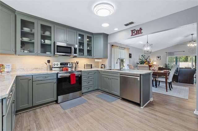 kitchen with sink, pendant lighting, vaulted ceiling, appliances with stainless steel finishes, and light wood-type flooring