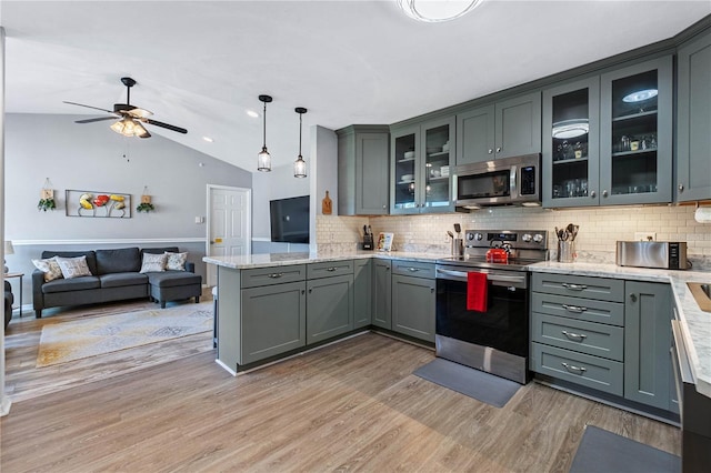 kitchen featuring pendant lighting, lofted ceiling, light wood-type flooring, kitchen peninsula, and stainless steel appliances