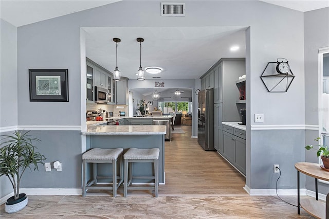 kitchen featuring gray cabinetry, stainless steel appliances, light hardwood / wood-style flooring, kitchen peninsula, and pendant lighting