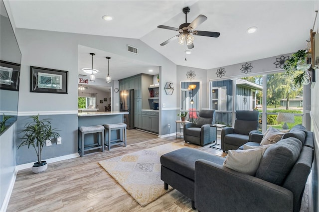 living room with ceiling fan, light hardwood / wood-style floors, and vaulted ceiling