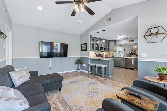 living room with light hardwood / wood-style flooring, ceiling fan, lofted ceiling, and sink