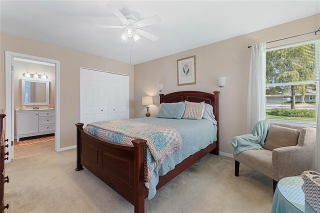 bedroom featuring ceiling fan, ensuite bathroom, light carpet, and a closet