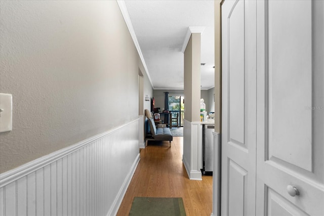 corridor with light wood-type flooring and ornamental molding