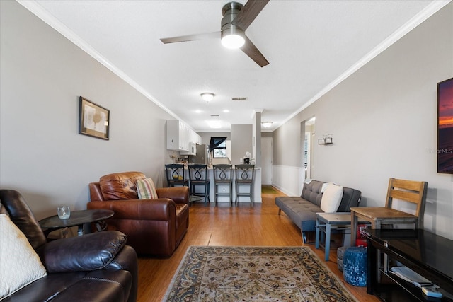 living room with wood-type flooring, ceiling fan, and ornamental molding