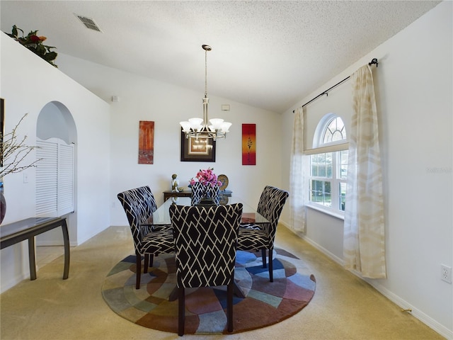 dining room with lofted ceiling, light colored carpet, visible vents, a textured ceiling, and a chandelier