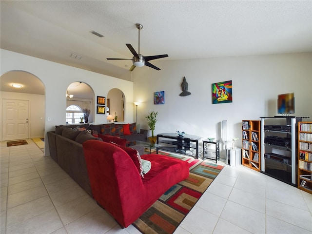 living area with light tile patterned floors, visible vents, arched walkways, a ceiling fan, and vaulted ceiling