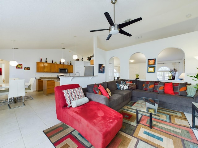 living room with light tile patterned floors, visible vents, vaulted ceiling, and arched walkways