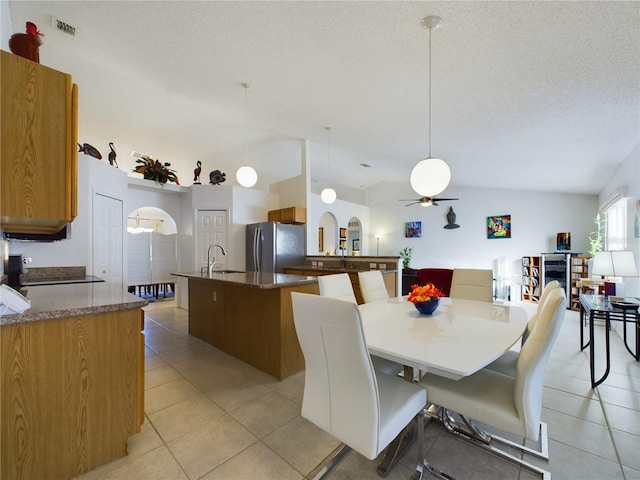 dining area with arched walkways, ceiling fan, a textured ceiling, light tile patterned flooring, and visible vents