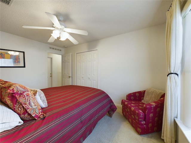 carpeted bedroom with a closet, visible vents, ceiling fan, and a textured ceiling