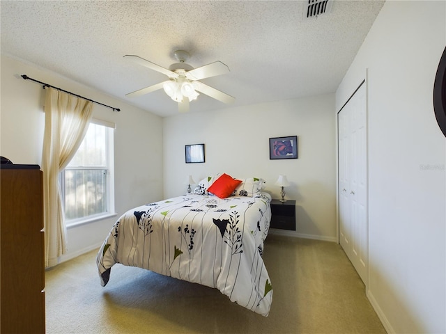 bedroom with baseboards, visible vents, a textured ceiling, and light colored carpet