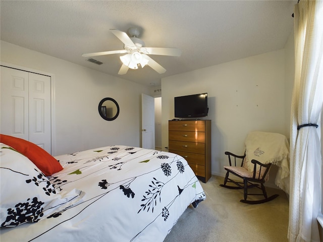 carpeted bedroom featuring a closet, visible vents, ceiling fan, and a textured ceiling