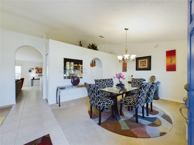 dining room featuring arched walkways, a notable chandelier, light tile patterned floors, visible vents, and vaulted ceiling