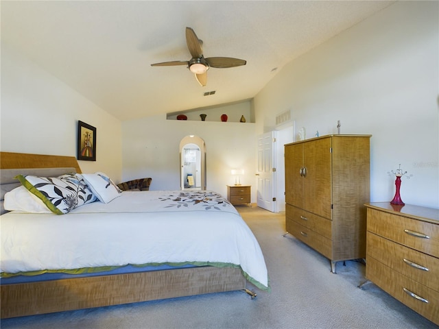 bedroom featuring lofted ceiling, visible vents, arched walkways, and light colored carpet