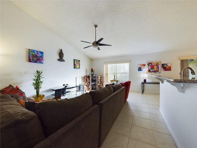 living room with lofted ceiling, ceiling fan, a textured ceiling, and light tile patterned floors