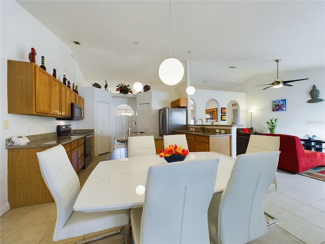 dining space with light tile patterned floors, arched walkways, and vaulted ceiling