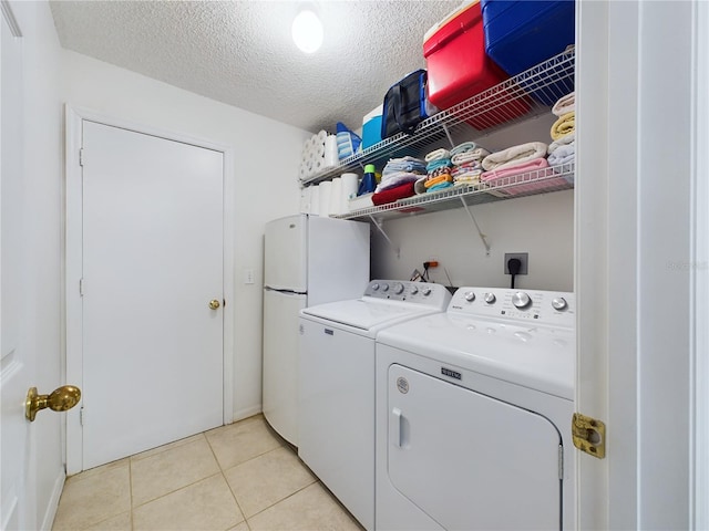 washroom featuring light tile patterned floors, laundry area, a textured ceiling, and washer and dryer