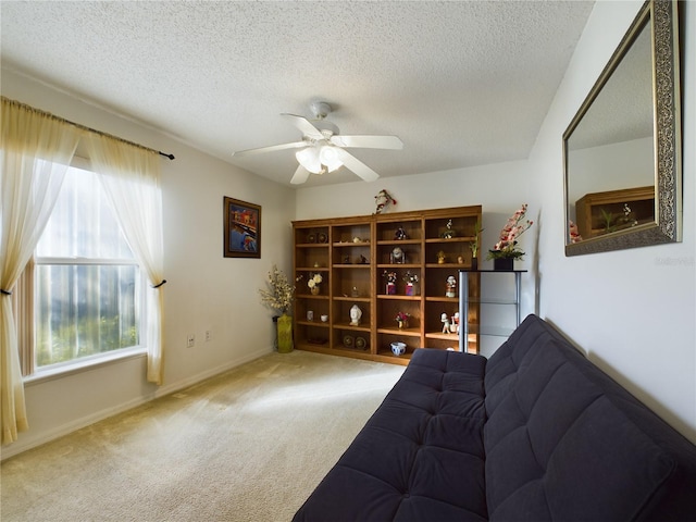 living area featuring a textured ceiling, ceiling fan, carpet flooring, and baseboards