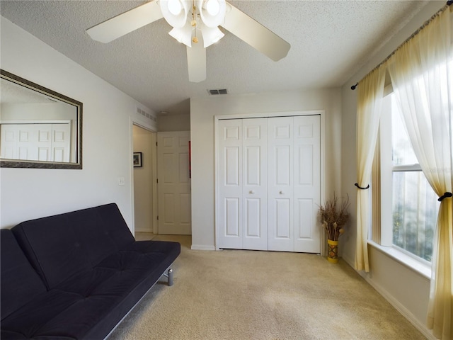 unfurnished room featuring light carpet, a wealth of natural light, a textured ceiling, and visible vents