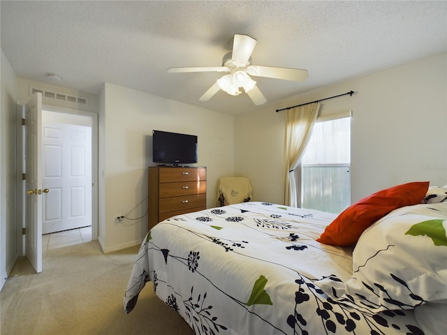 bedroom featuring a textured ceiling, light colored carpet, a ceiling fan, baseboards, and visible vents