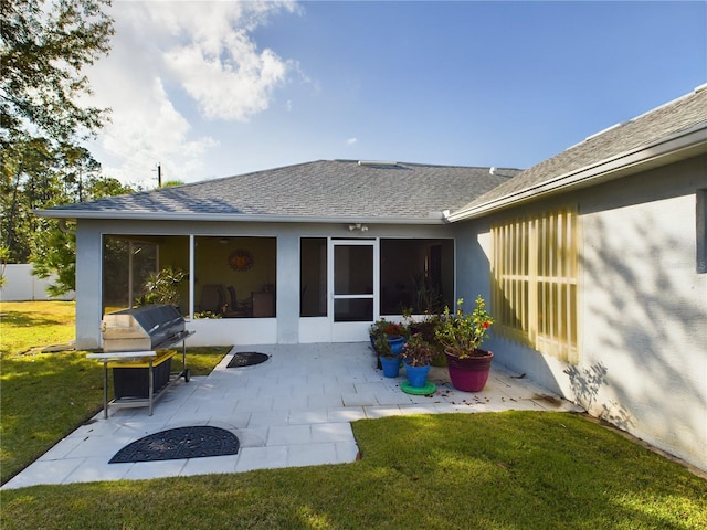 back of property featuring a patio, roof with shingles, a lawn, and a sunroom