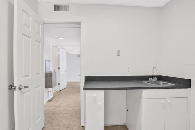 kitchen with white cabinets, light tile patterned floors, and sink