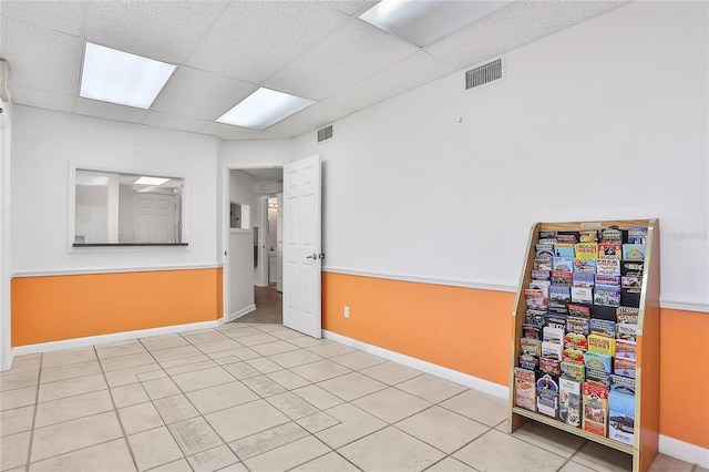 tiled empty room featuring a paneled ceiling