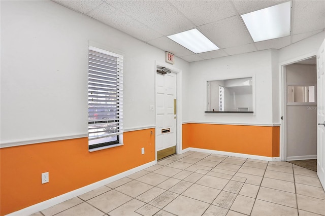 tiled empty room featuring a paneled ceiling