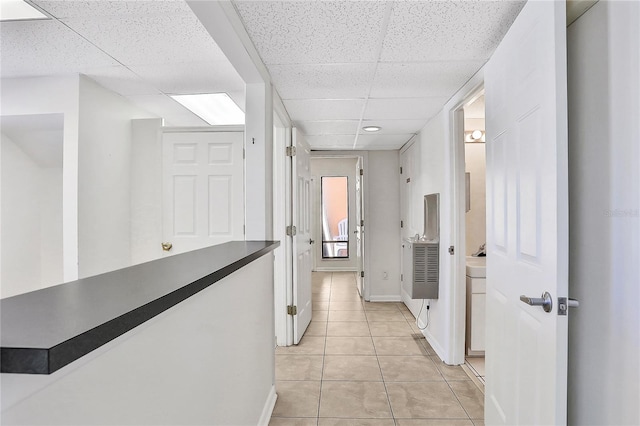 corridor with a drop ceiling and light tile patterned floors