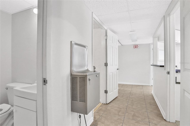 hallway featuring a drop ceiling and light tile patterned floors