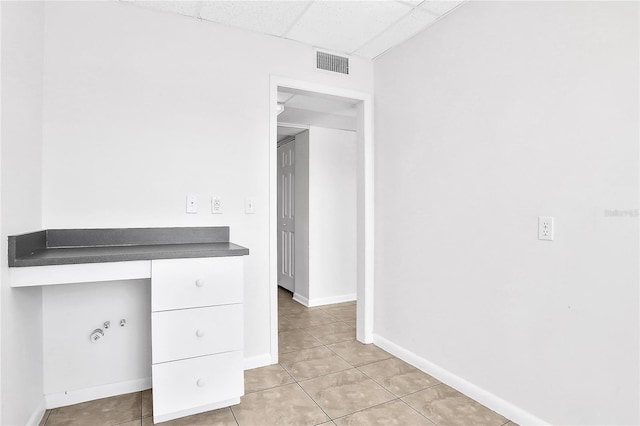 unfurnished office featuring a paneled ceiling and light tile patterned flooring