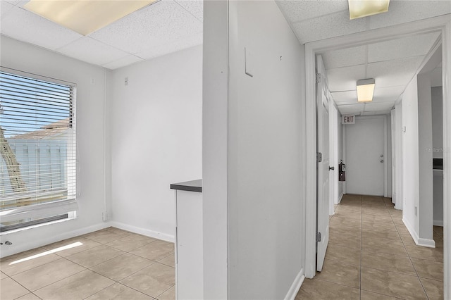 hallway featuring a drop ceiling, plenty of natural light, and light tile patterned floors