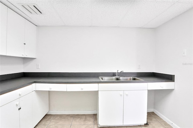 kitchen with light tile patterned flooring, white cabinetry, and sink