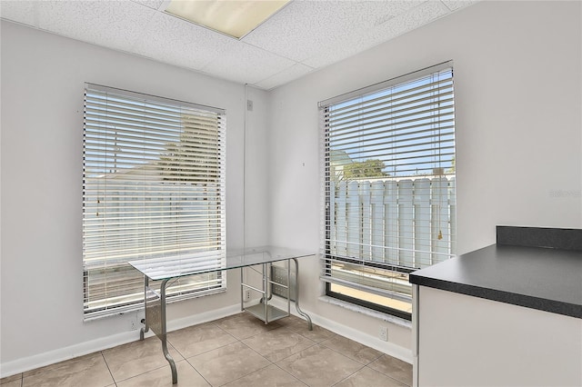 tiled dining area with a paneled ceiling