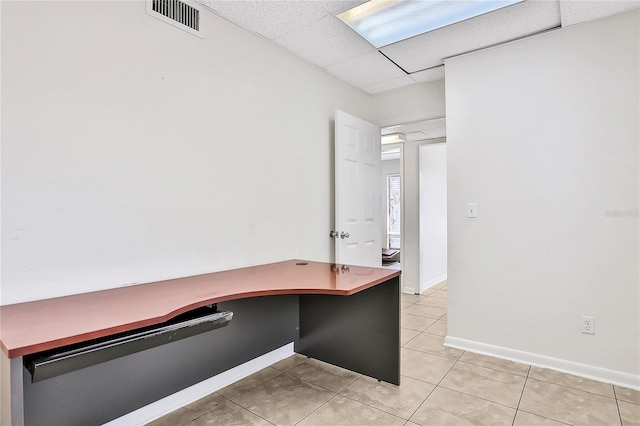 unfurnished office with a paneled ceiling and light tile patterned floors