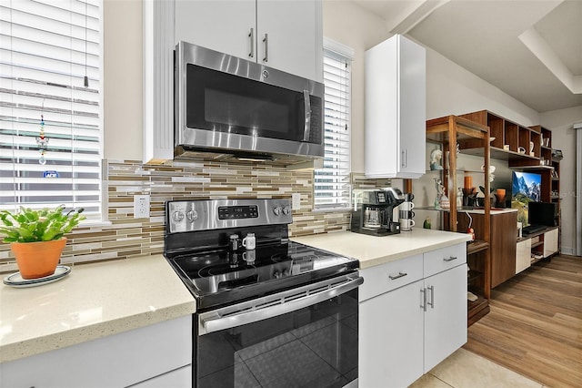 kitchen featuring a wealth of natural light, decorative backsplash, white cabinetry, and appliances with stainless steel finishes