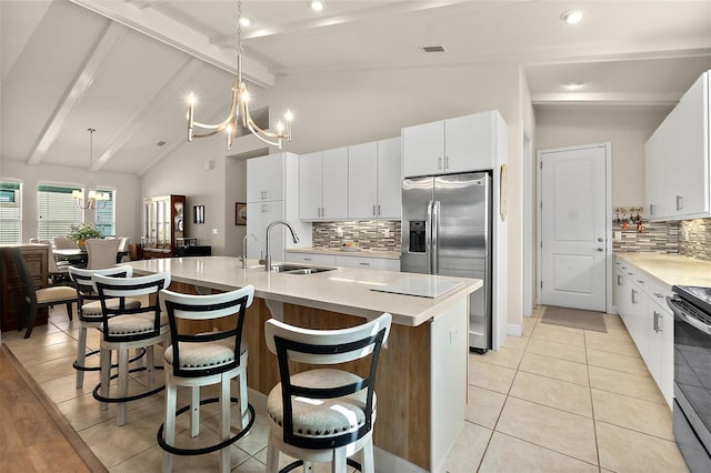 kitchen with backsplash, sink, beam ceiling, a center island with sink, and decorative light fixtures