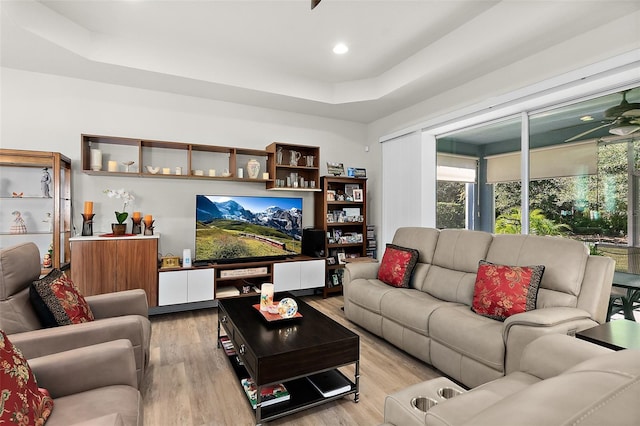 living room with light wood-type flooring and a tray ceiling