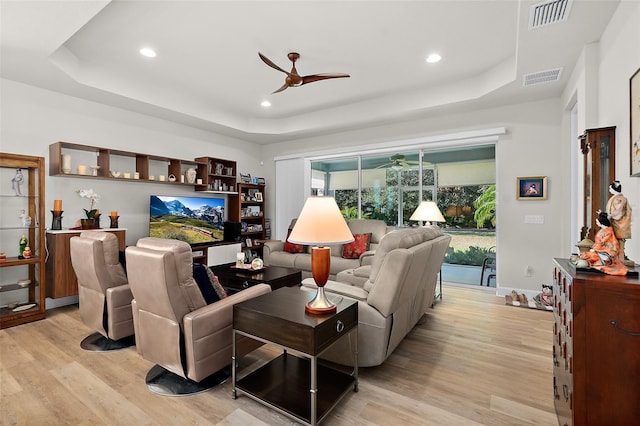 living room featuring a tray ceiling and light hardwood / wood-style floors