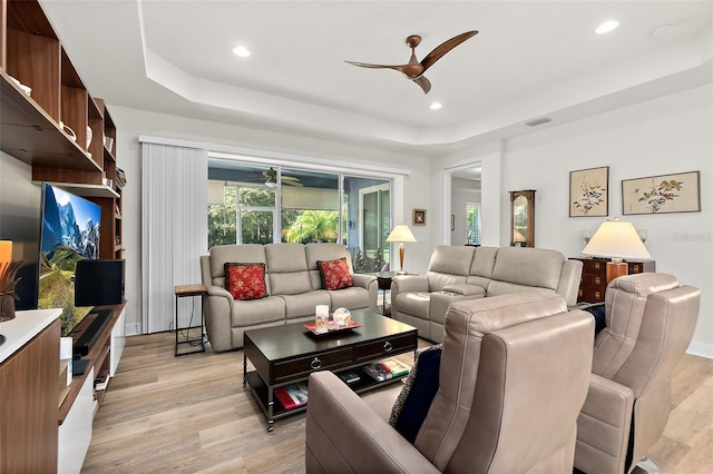 living room with a tray ceiling and light hardwood / wood-style flooring