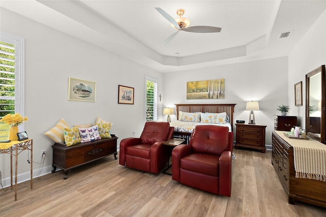 bedroom featuring a tray ceiling, ceiling fan, and light wood-type flooring