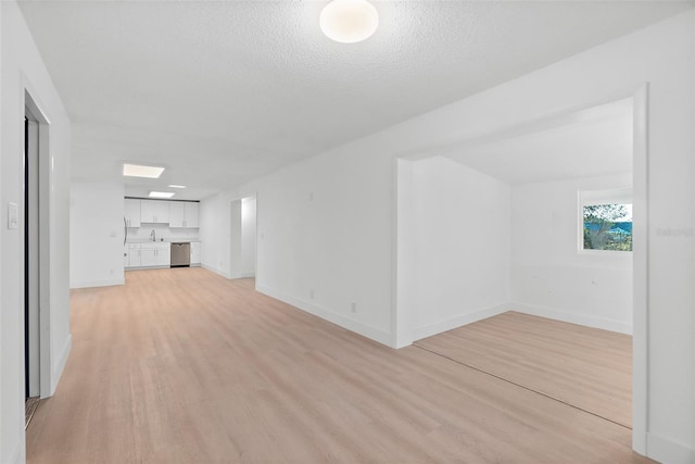 unfurnished living room featuring sink, a textured ceiling, and light wood-type flooring