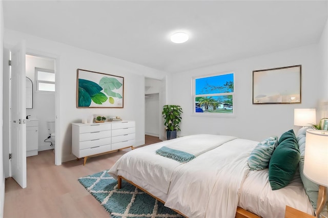 bedroom with light hardwood / wood-style floors and connected bathroom