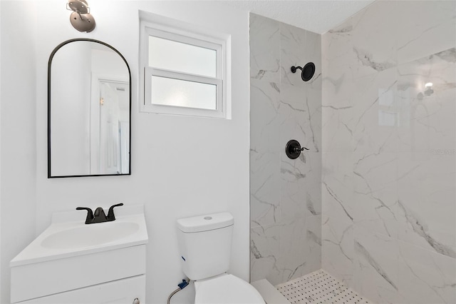 bathroom featuring vanity, toilet, and a tile shower