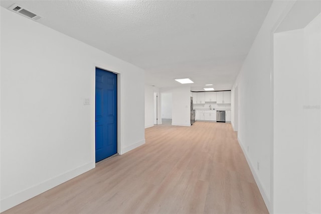 spare room featuring a textured ceiling and light wood-type flooring