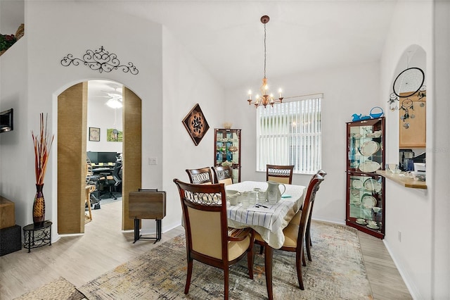 dining space with ceiling fan with notable chandelier and light wood-type flooring