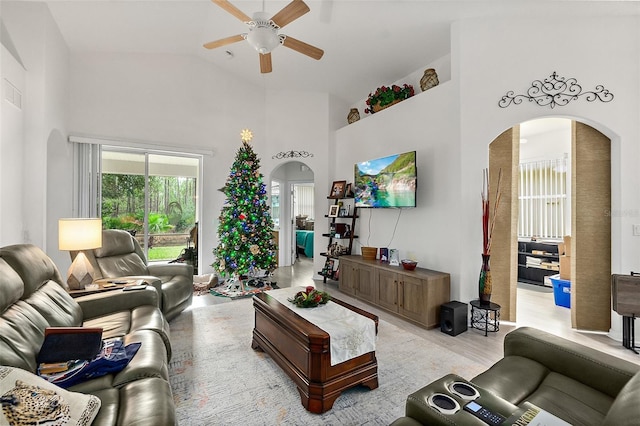 living room with ceiling fan, high vaulted ceiling, and light hardwood / wood-style flooring